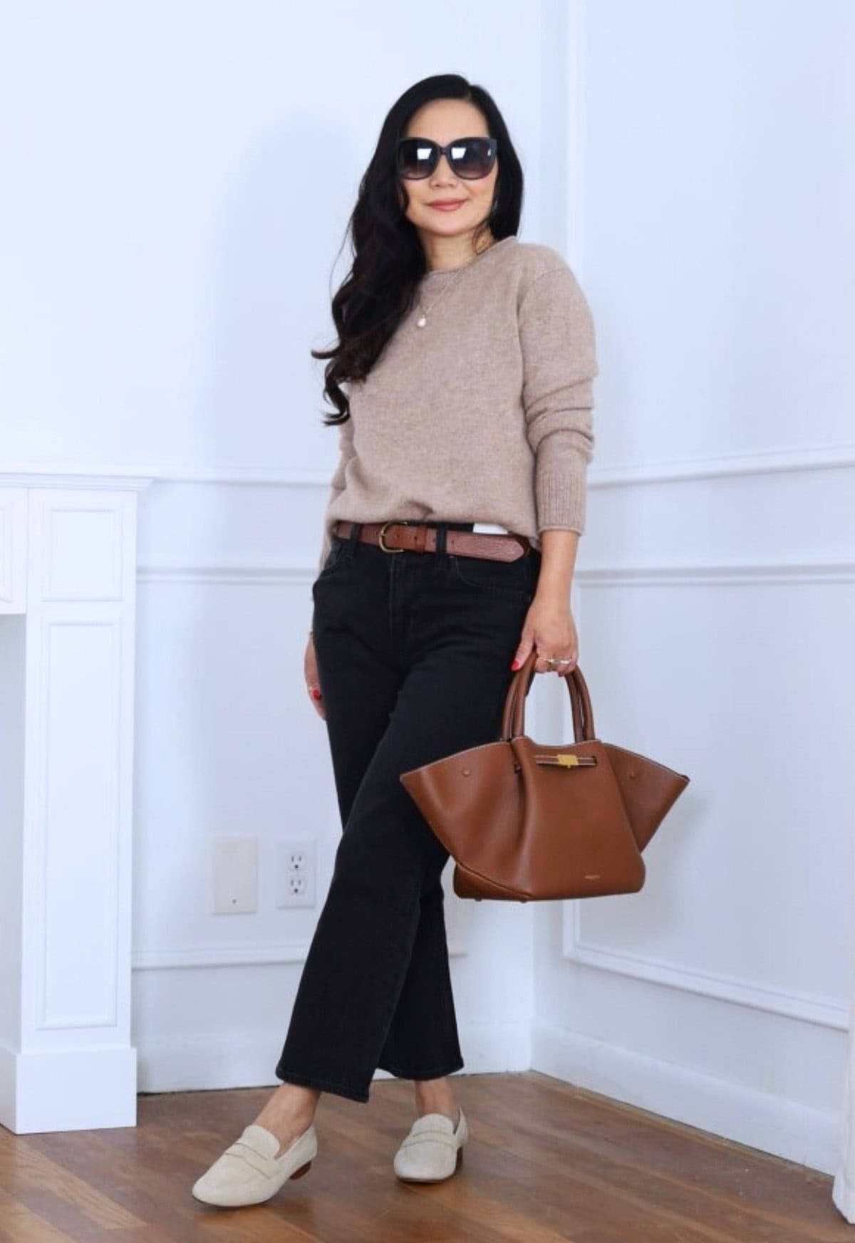 neutral crewneck sweater styled with dark straight-leg jeans and classic loafers