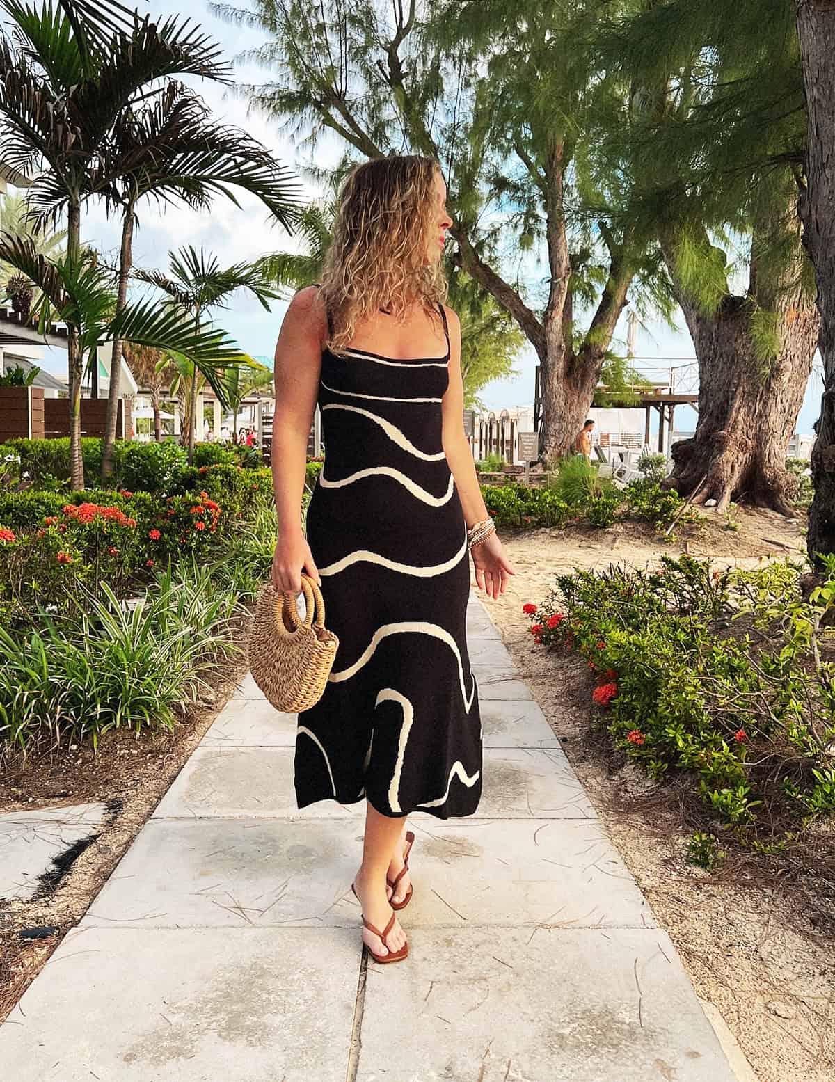 cancun vacation outfit with black midi dress and straw bag