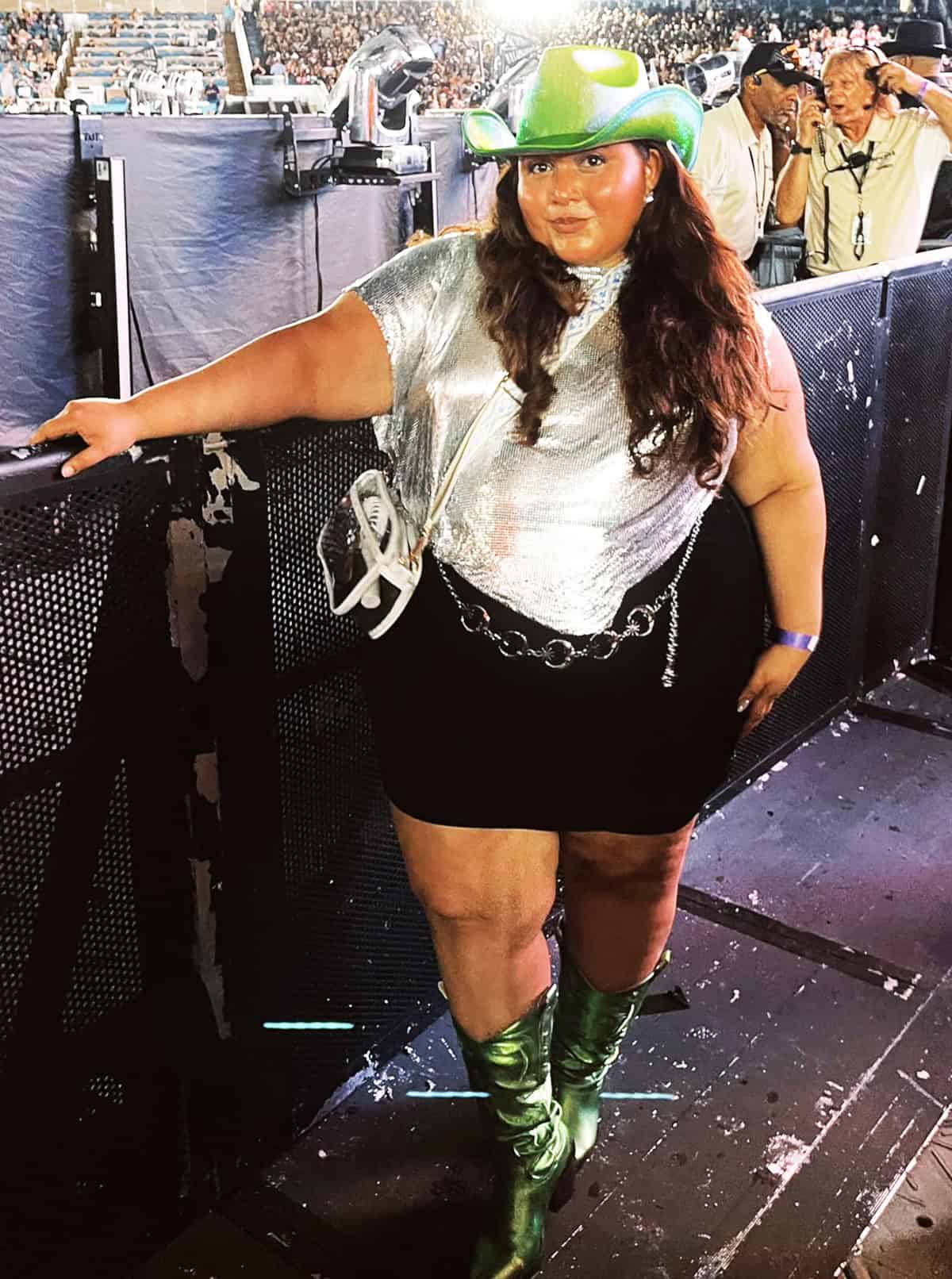 silver metallic top and black mini skirt with green cowboy hat and boots for festival outfits for plus size women