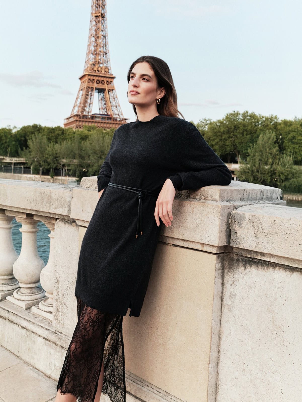 black sweater dress layered over a lace skirt styled for a winter cocktail outfit