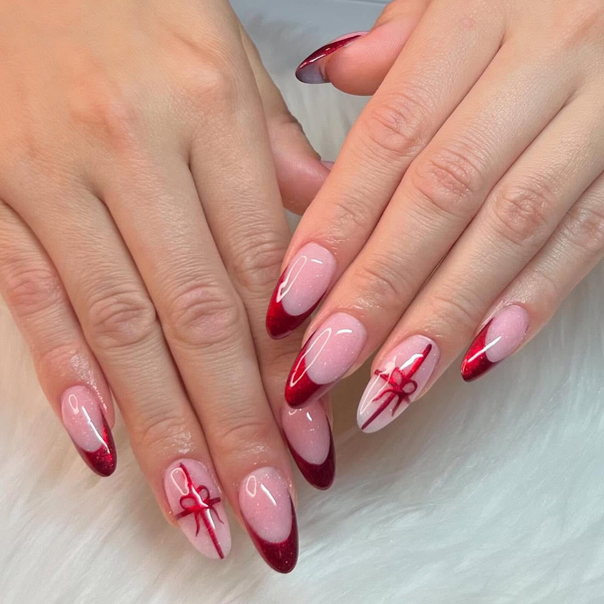 almond nails with sheer pink base and red chrome tips with bow detail red chrome nails