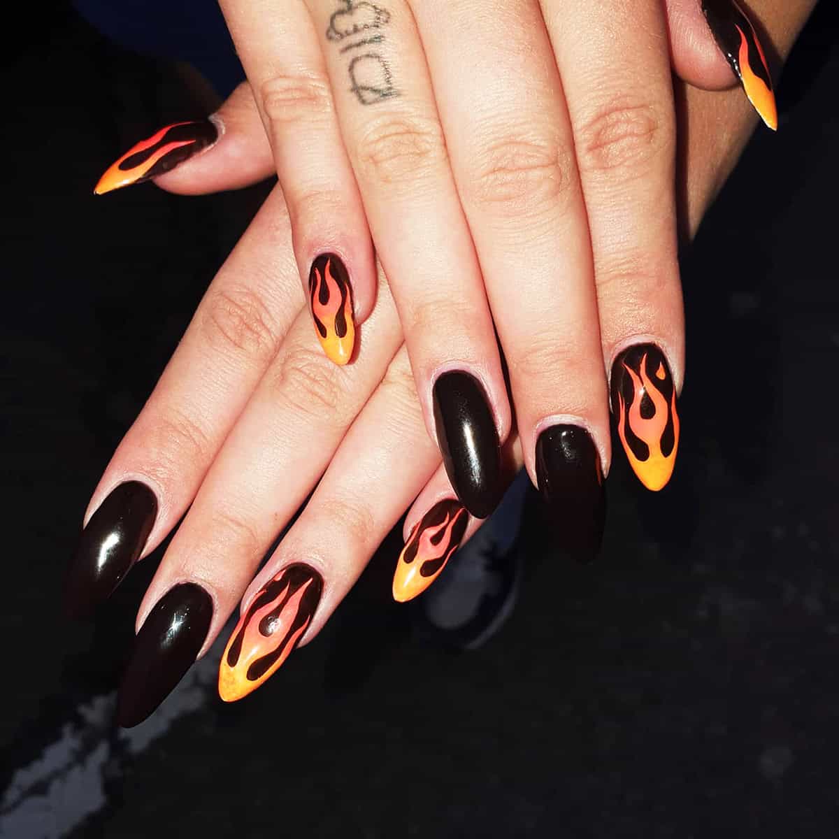 black almond nails with orange and yellow flame accents on select nails fire nails
