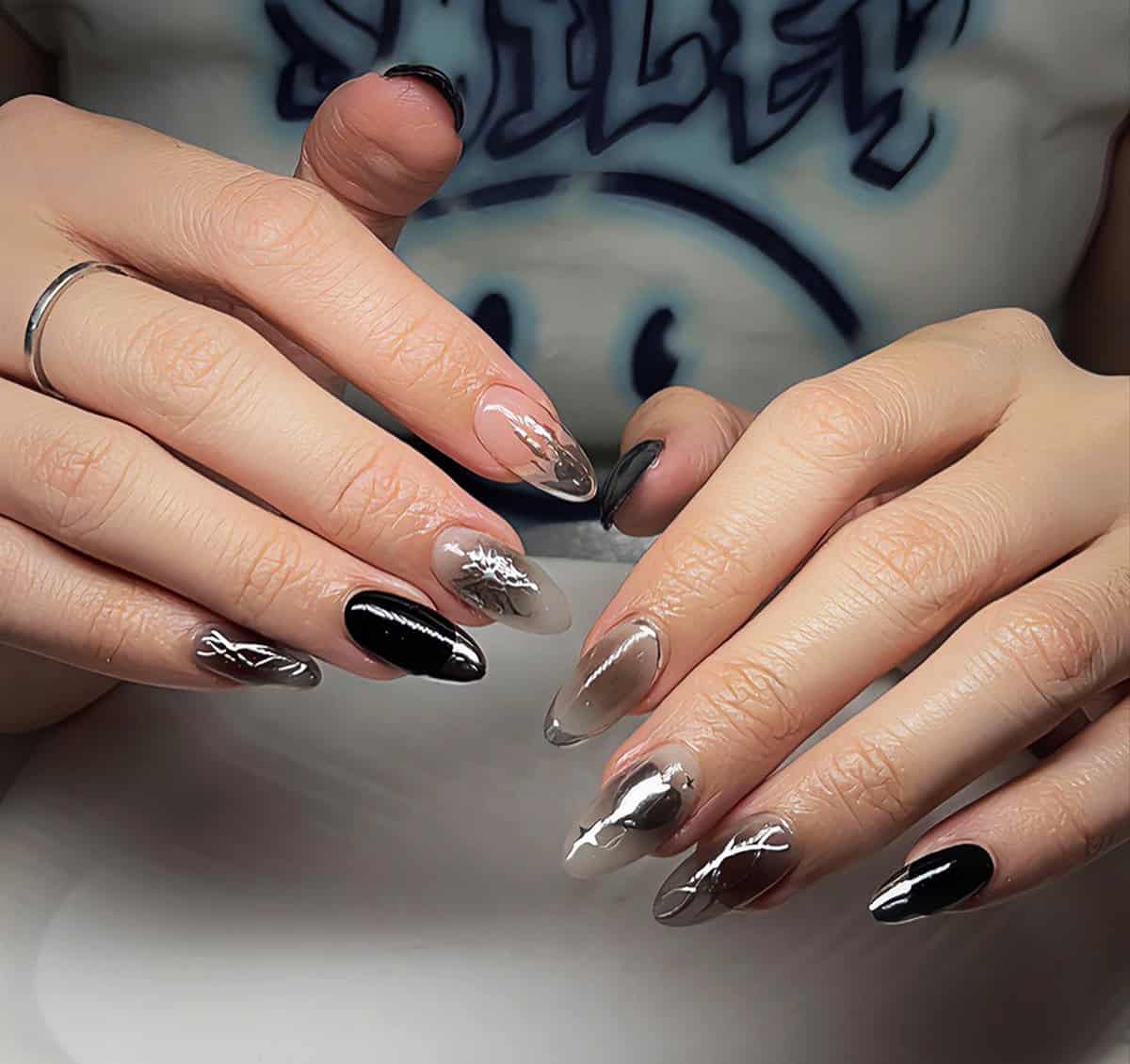 abstract black chrome swirl design on almond nails with nude base black chrome nails