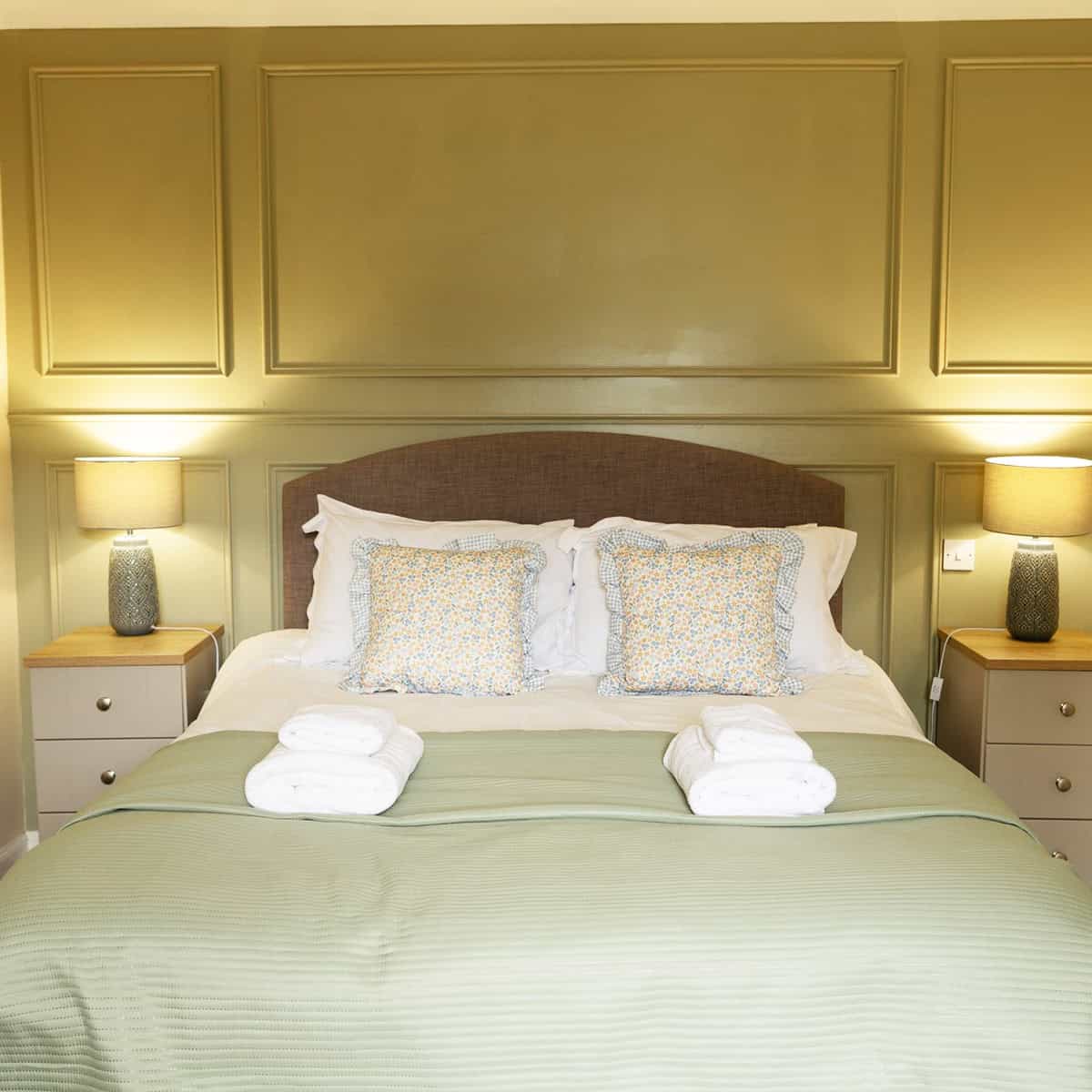 green paneled wall with symmetrical lamps and floral pillows, tidy cozy bedroom cottagecore bedroom insp