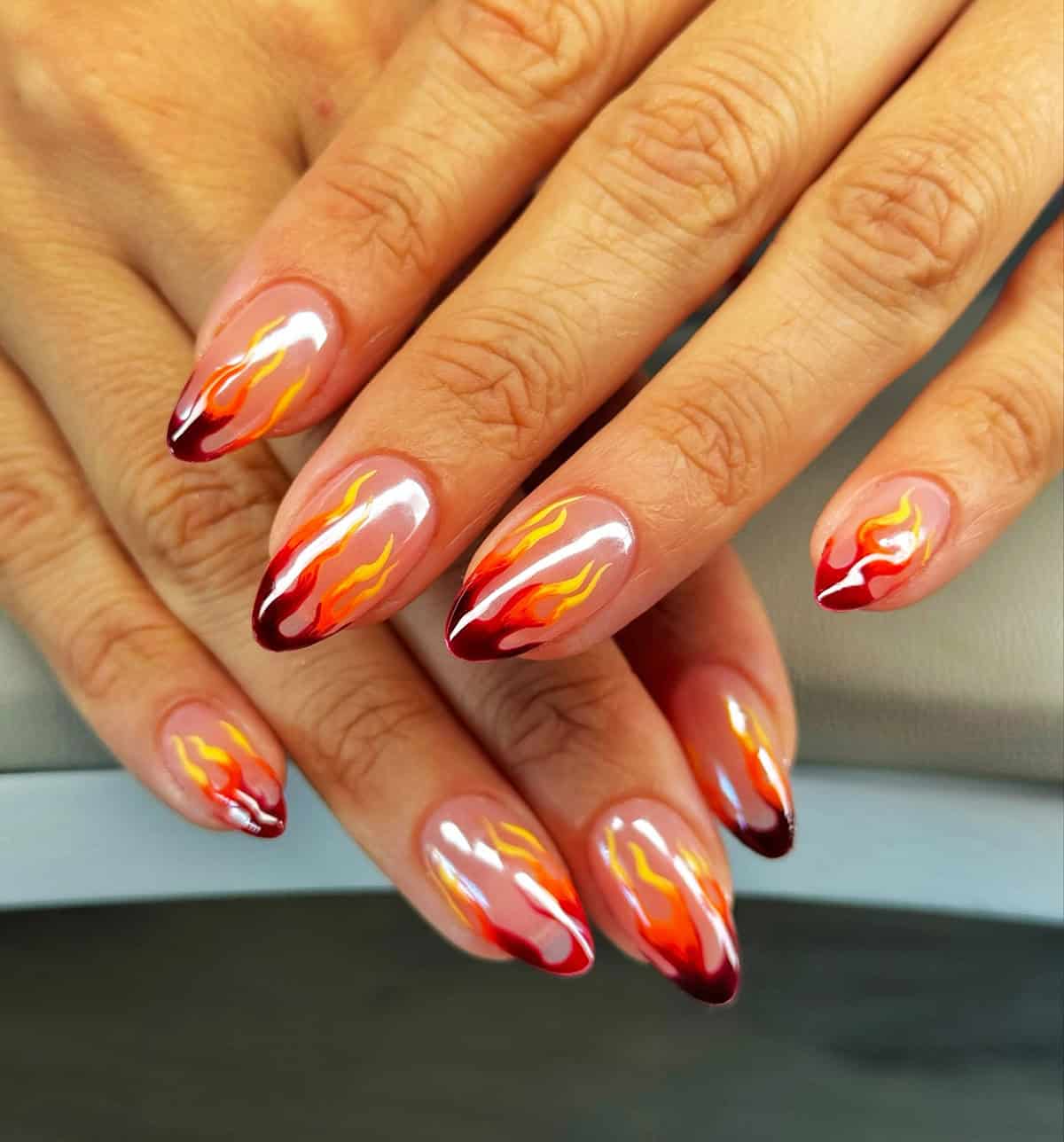 sheer nude almond nails with realistic red orange and yellow flame nail art fire nails