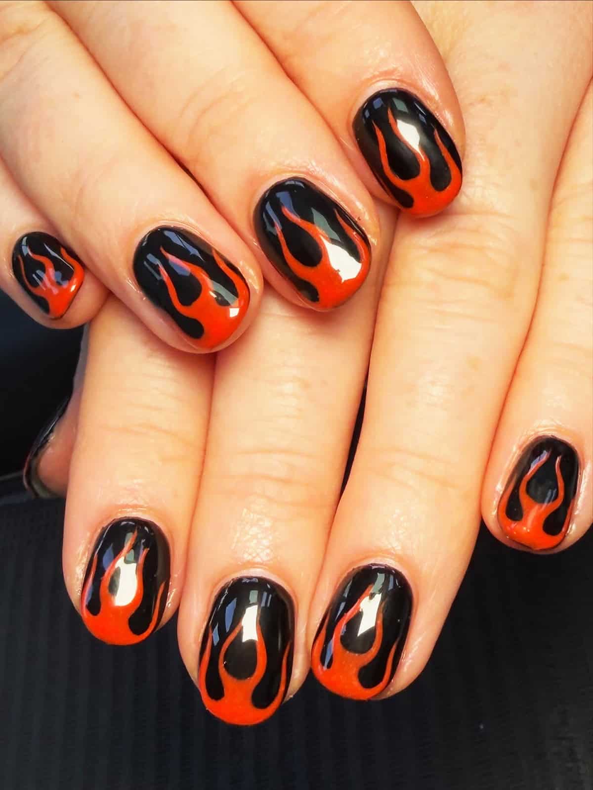 short round black nails with red-orange flame outlines on every nail fire nails