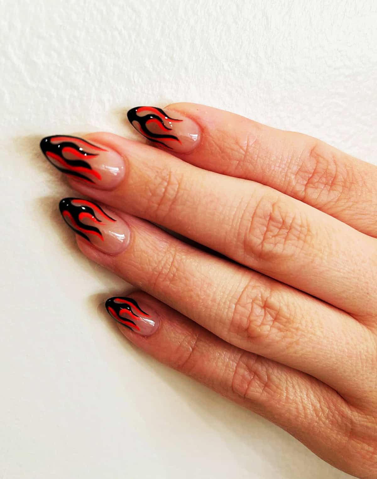 almond nude nails with black and red flame tips in a goth French tip style fire nails