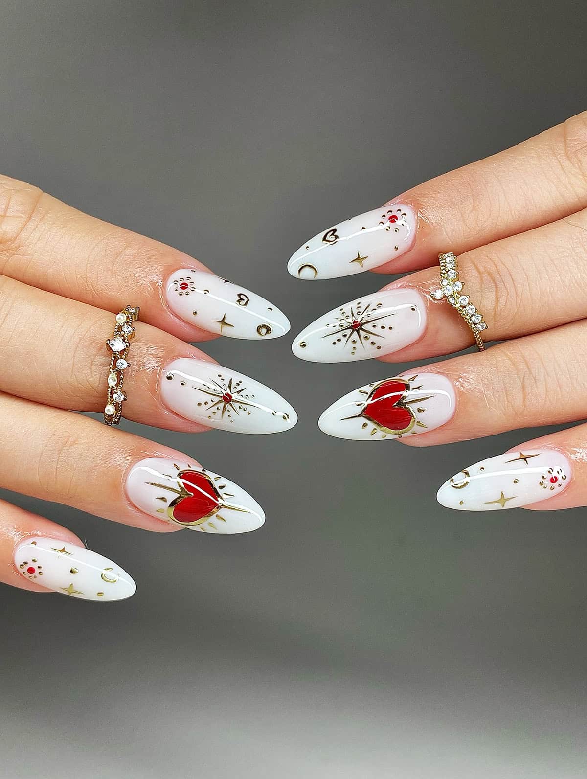 white almond nails with gold celestial nail art and red heart accents white chrome nails