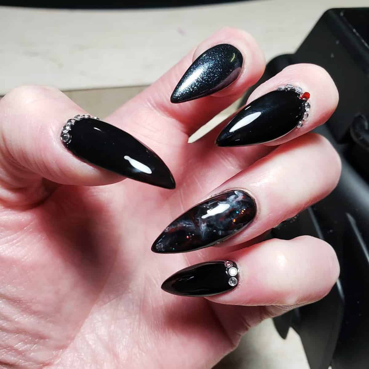 almond nails with black chrome, shimmer, and rhinestone accents black chrome nails