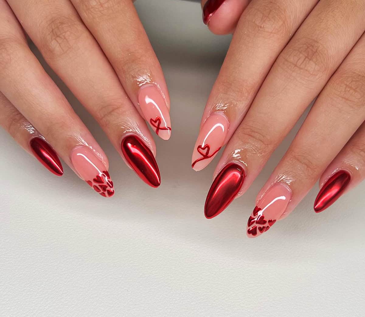 almond nude and red chrome nails with small heart designs red chrome nails