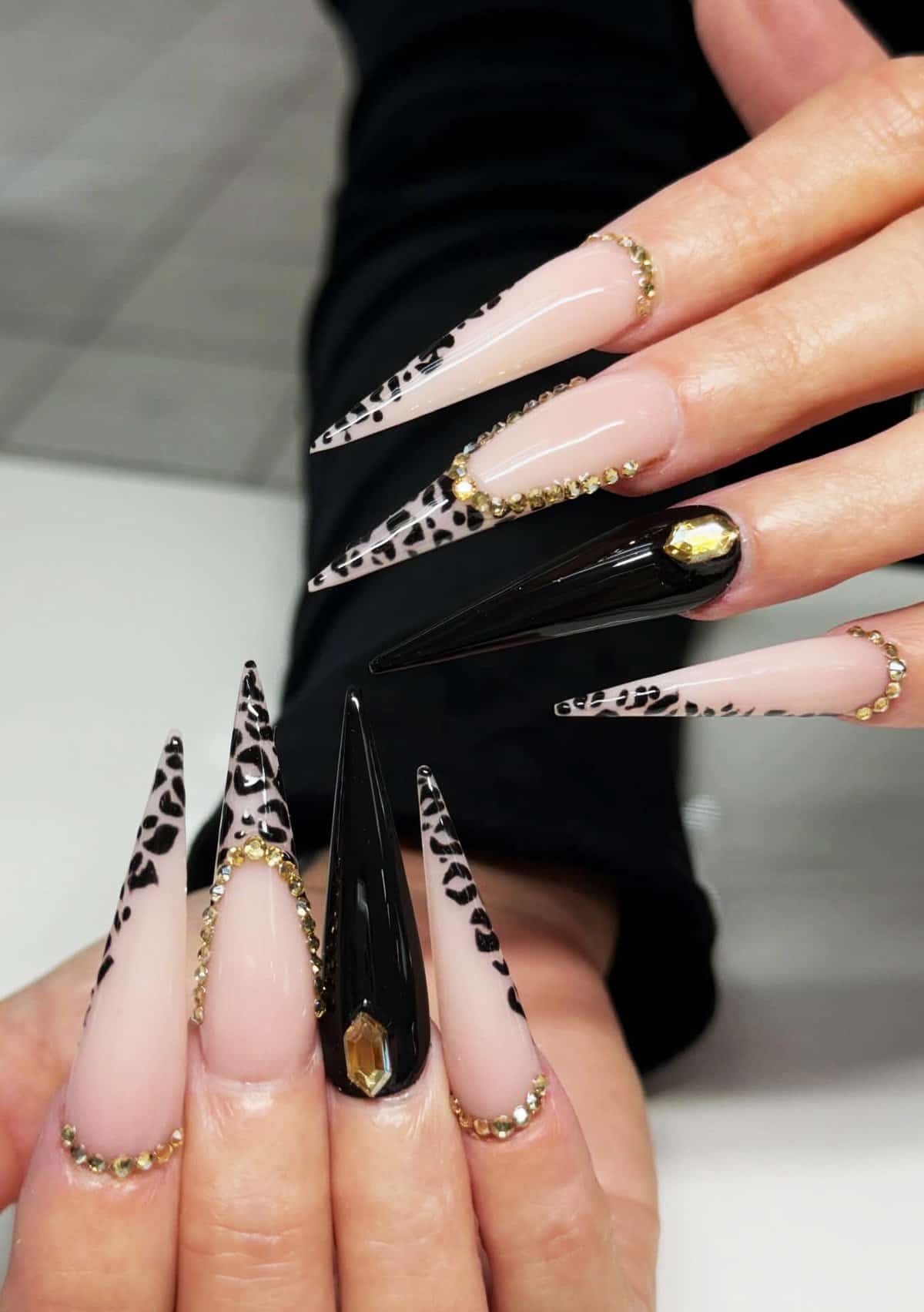 long stiletto nails with nude base, black leopard print, and gold rhinestone accents, luxury black baddie nails