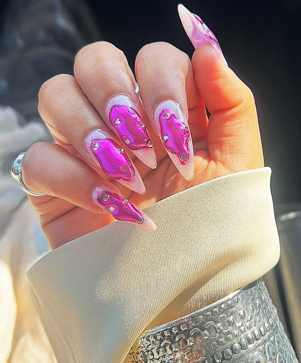 almond stiletto nails with pink chrome drip accent design and rhinestones glossy bold pink chrome nails