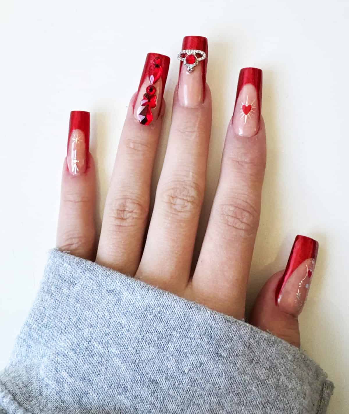 long square red chrome nails with rhinestones hearts and gem accents bold glam design red chrome nails