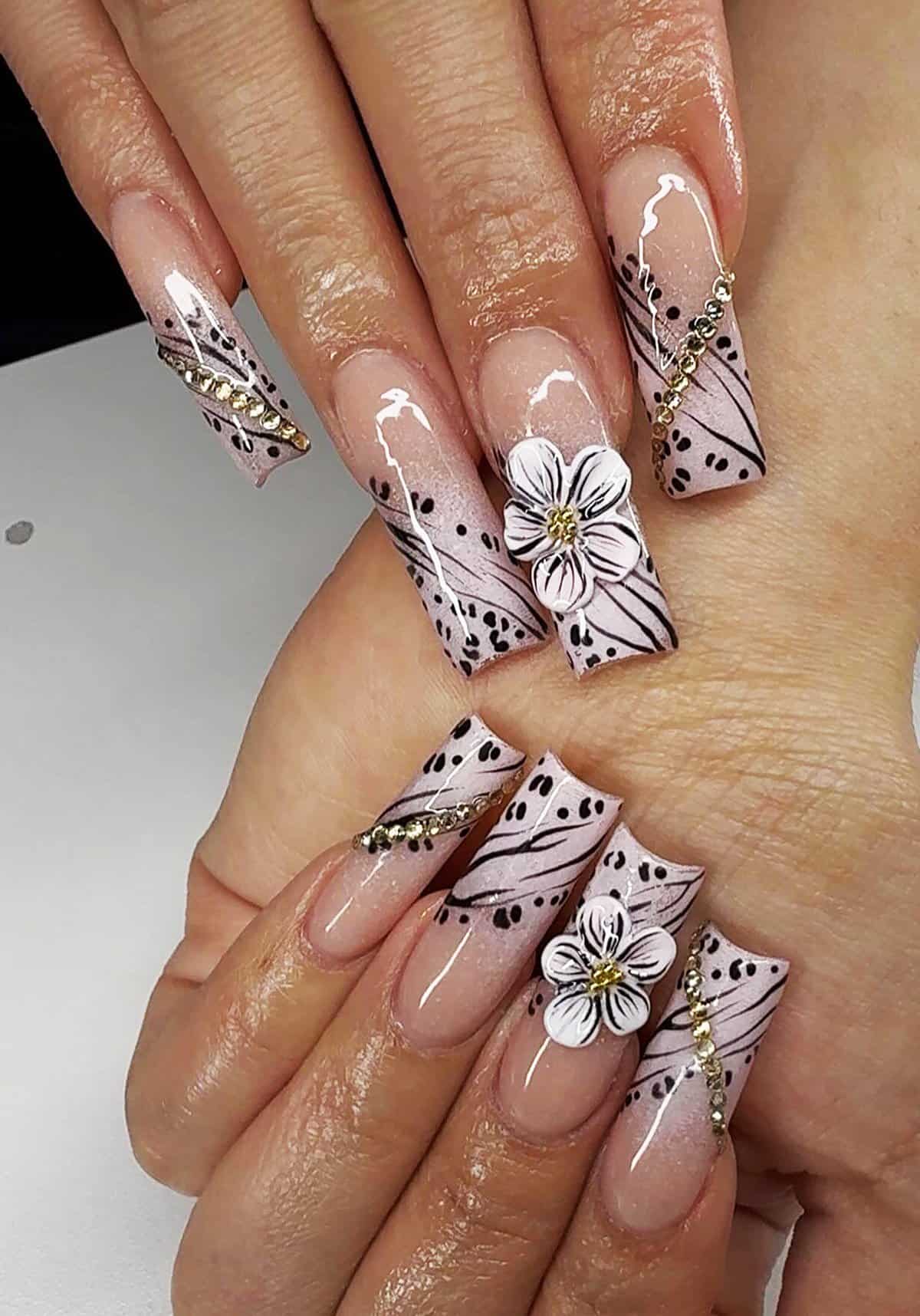long coffin nails with pink base, black line art, gold accents, and 3D flowers, glam black baddie nails