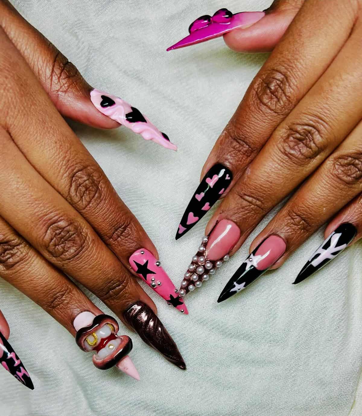 long stiletto pink and black nails with hearts, stars, pearls, and mixed nail art details baddie nails for summer