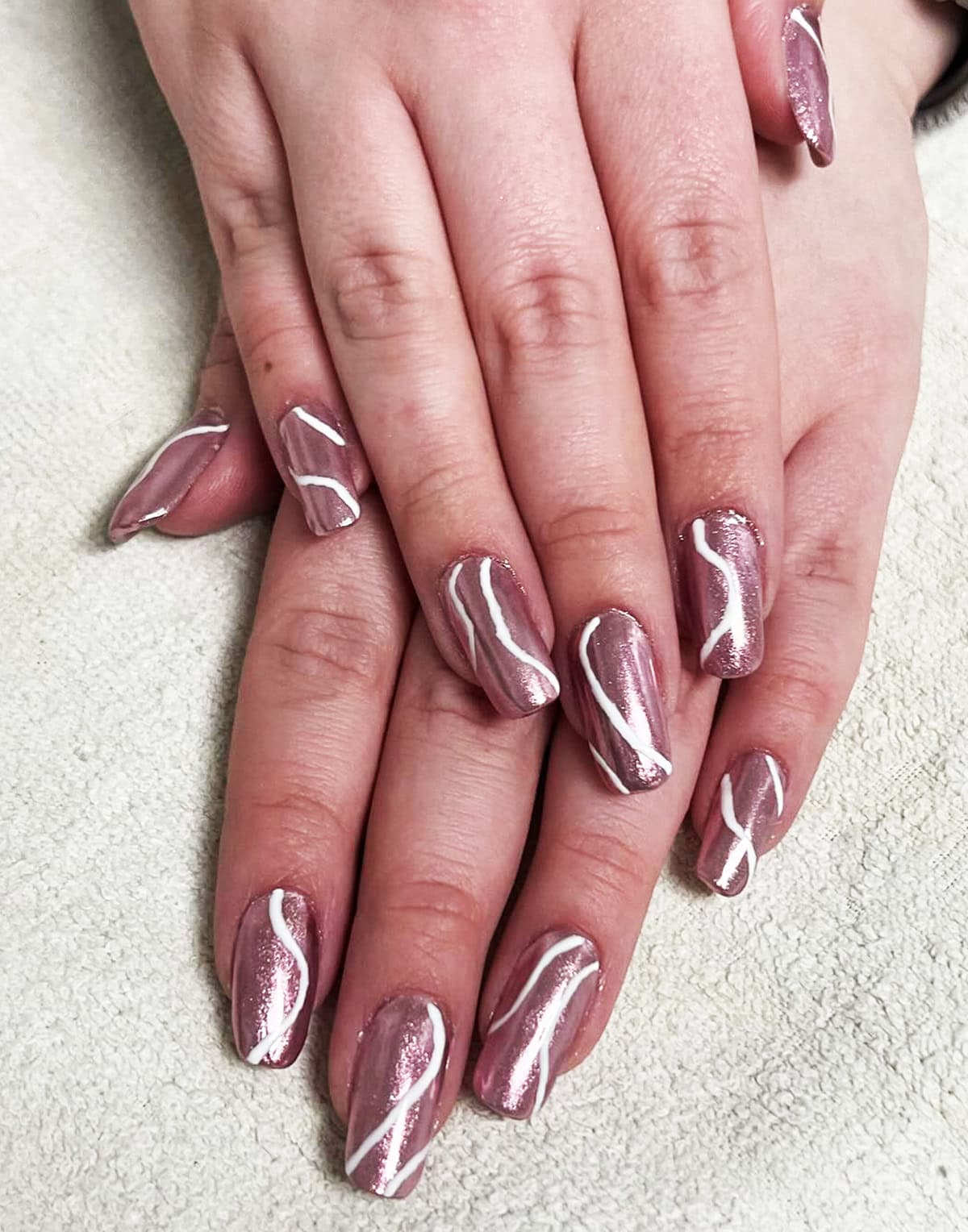 soft pink chrome almond nails with white swirl design glossy finish pink chrome nails
