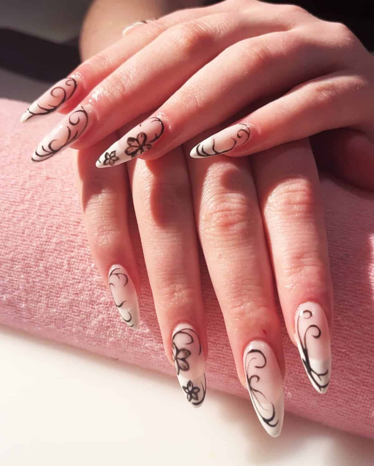 almond nails with milky base and thin black swirl designs, soft feminine black baddie nails