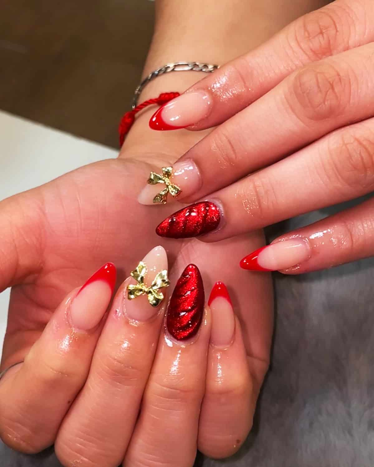 almond red chrome glitter nails with gold bow accents design red chrome nails