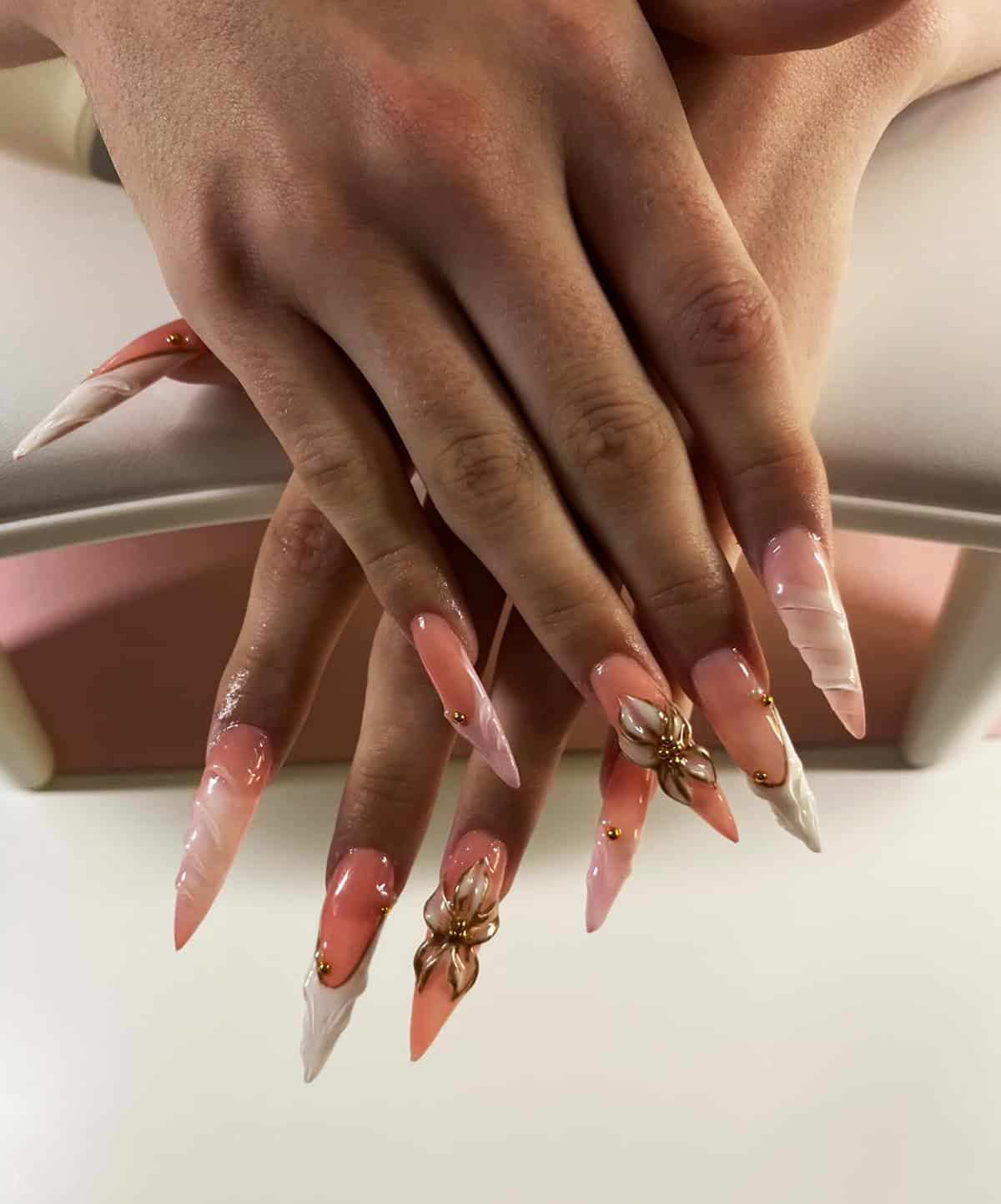 peach nude nails with marble tips, gold accents, and 3D flower detail baddie nails for summer