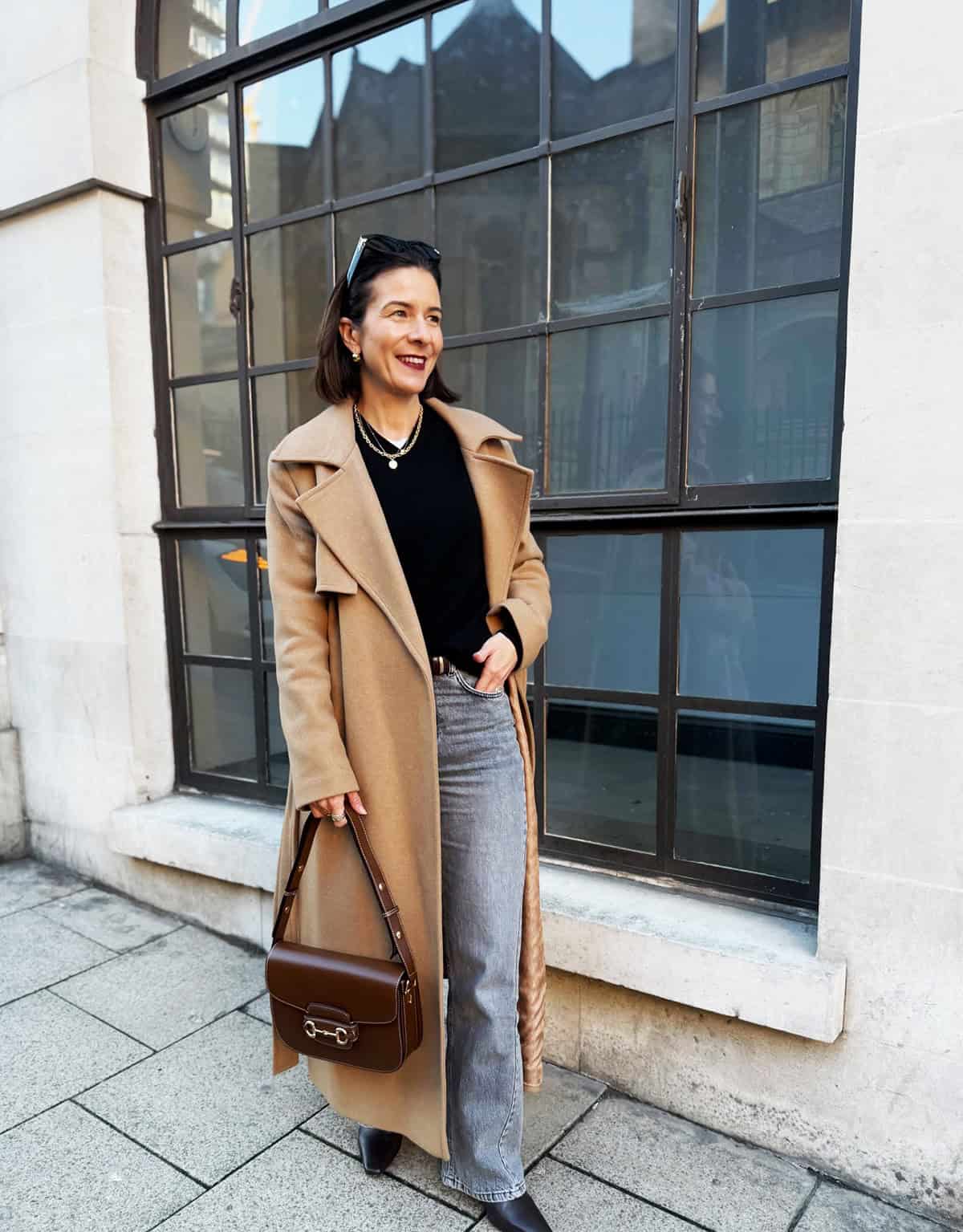 camel wool coat over black sweater with grey wide-leg jeans and black ankle boots for office attire for women over 40