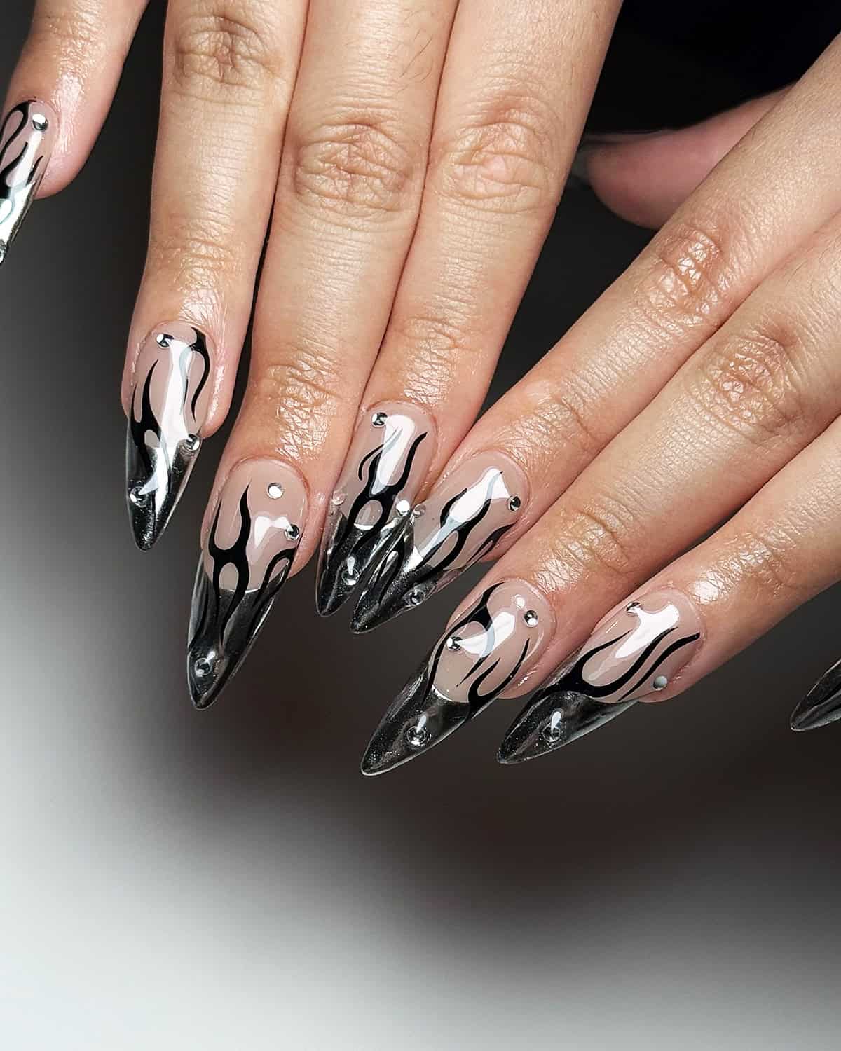 stiletto nails with black chrome drip flame design over nude base black chrome nails