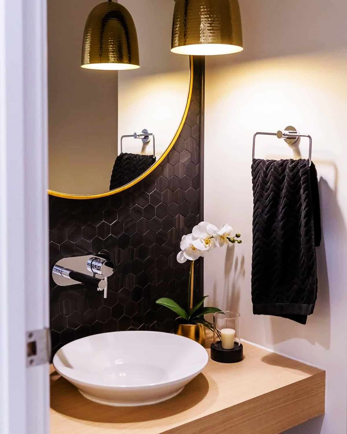 black hexagon tile backsplash in bathroom with wood vanity and warm lighting black bathroom ideas