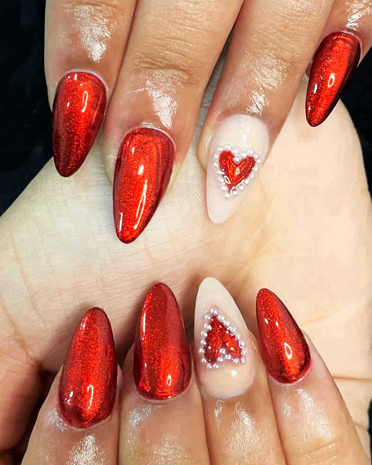 almond red chrome nails with rhinestone heart accent on nude base red chrome nails