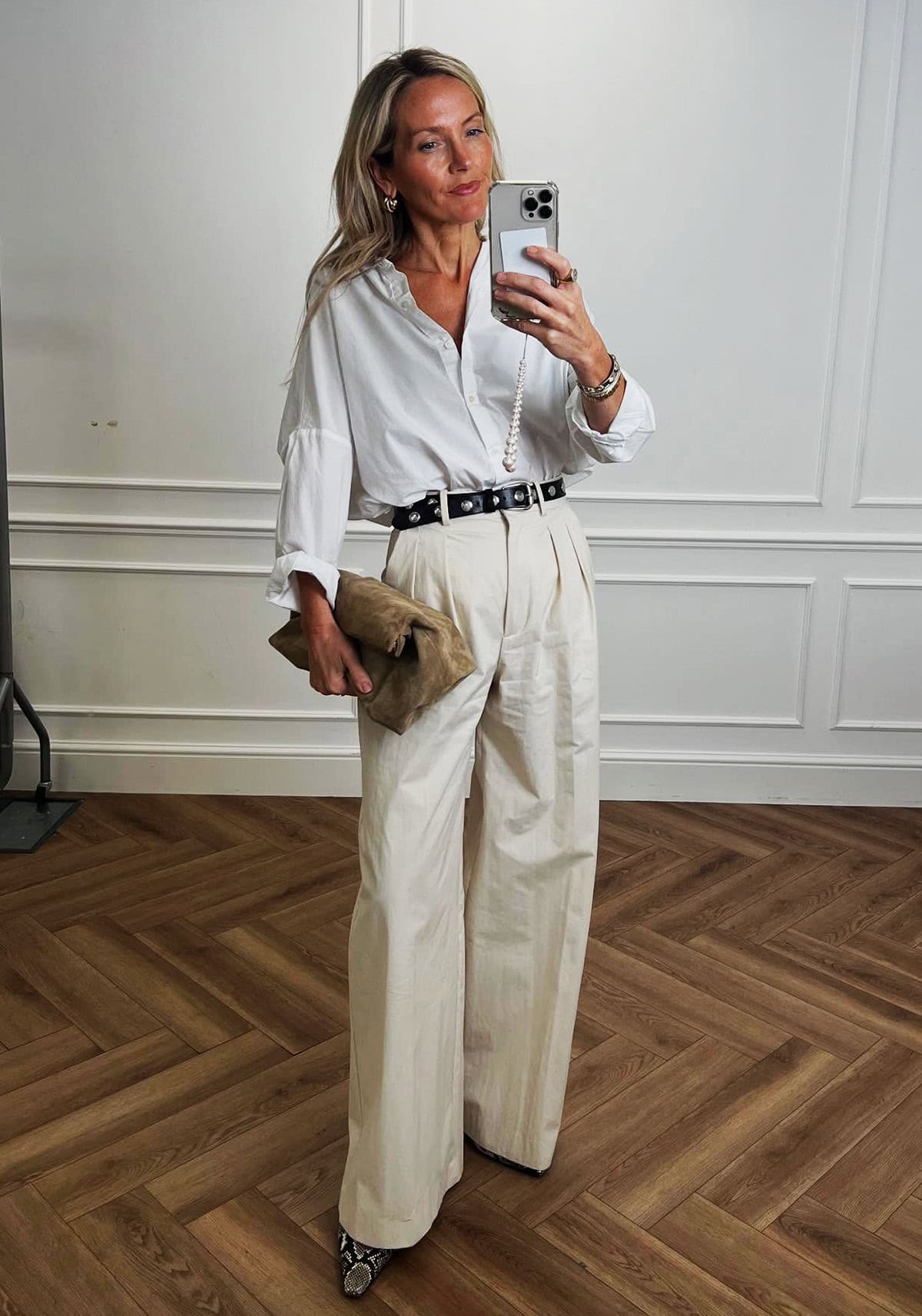 white button-down shirt with wide-leg cream trousers, black studded belt and snake-print mules for office attire for women over 40