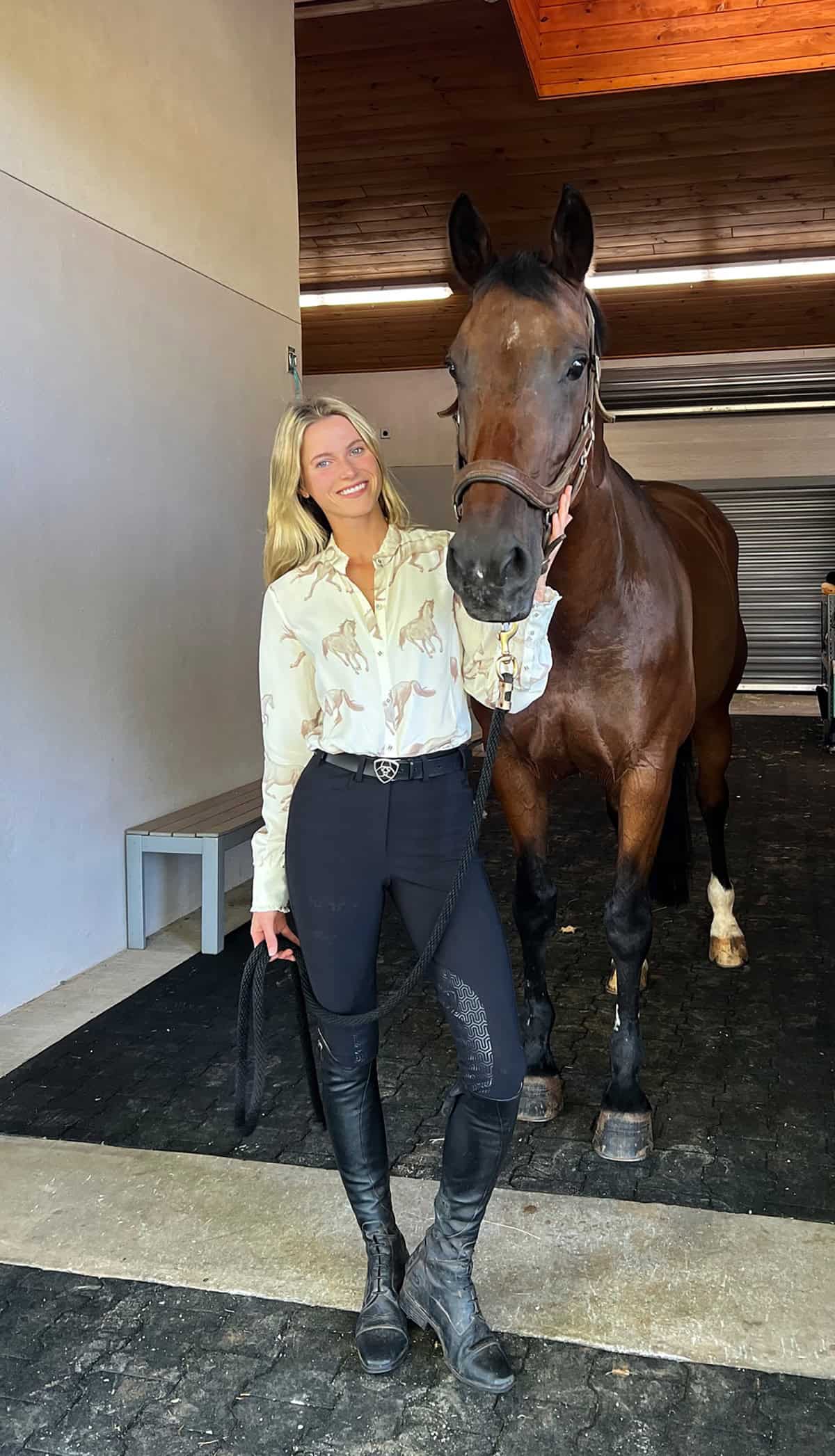 rider in printed button-down shirt tucked into black breeches with tall riding boots for a best equestrian outfits for English riding