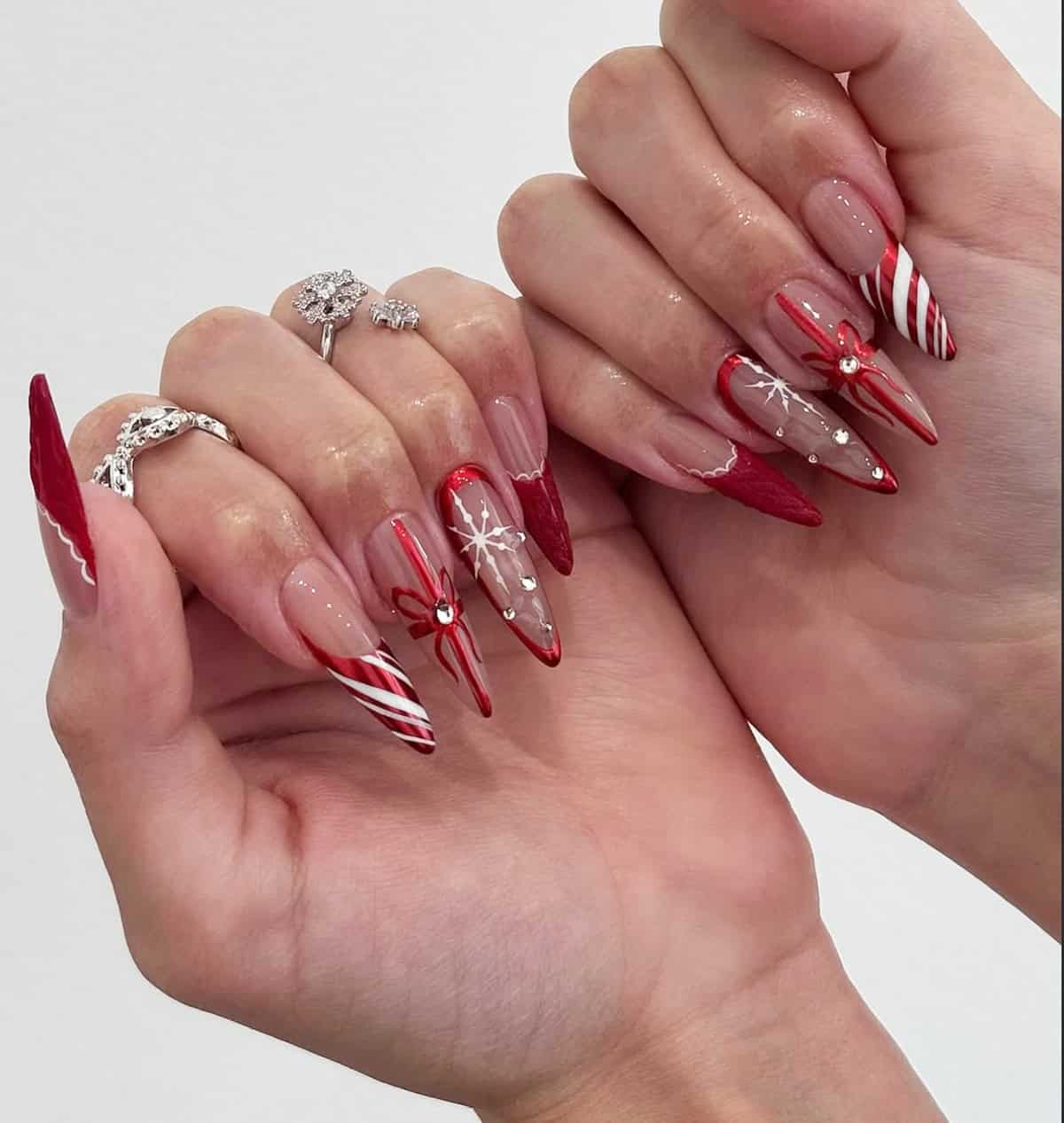 festive red chrome stiletto nails with snowflakes candy cane stripes and bow details red chrome nails