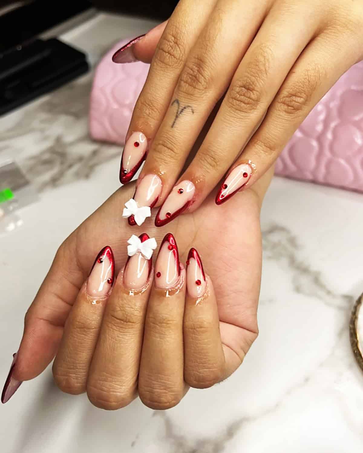 almond nude nails with red chrome tips gems and bow details red chrome nails