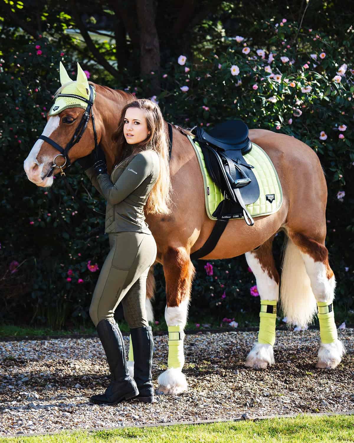 olive green matching breeches and fitted long sleeve top with black tall boots and coordinated saddle pad for best equestrian outfits for English riding