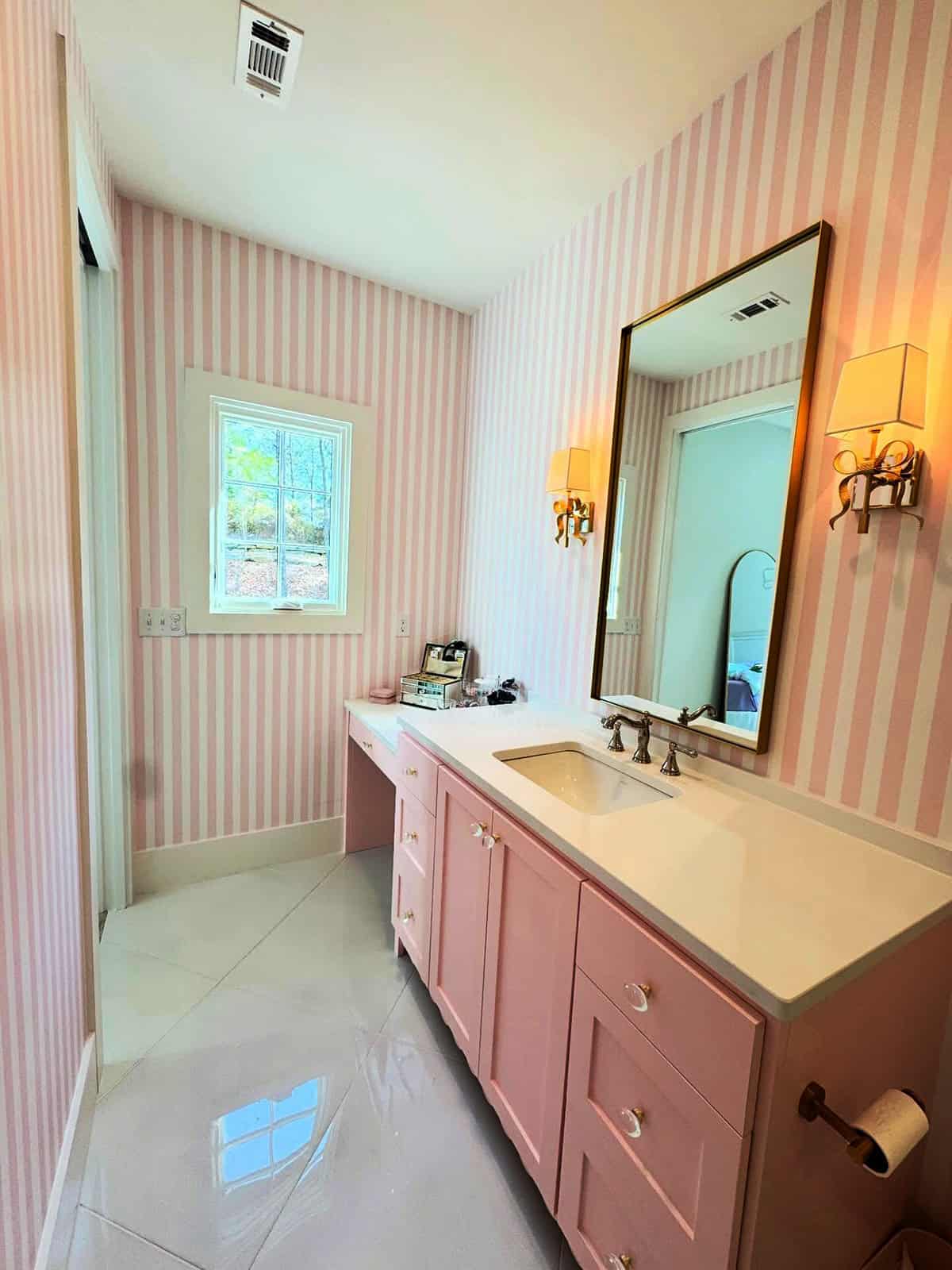 pink and white medium stripe wallpaper in a bathroom with pink painted vanity and gold sconces pink wallpaper ideas home decor