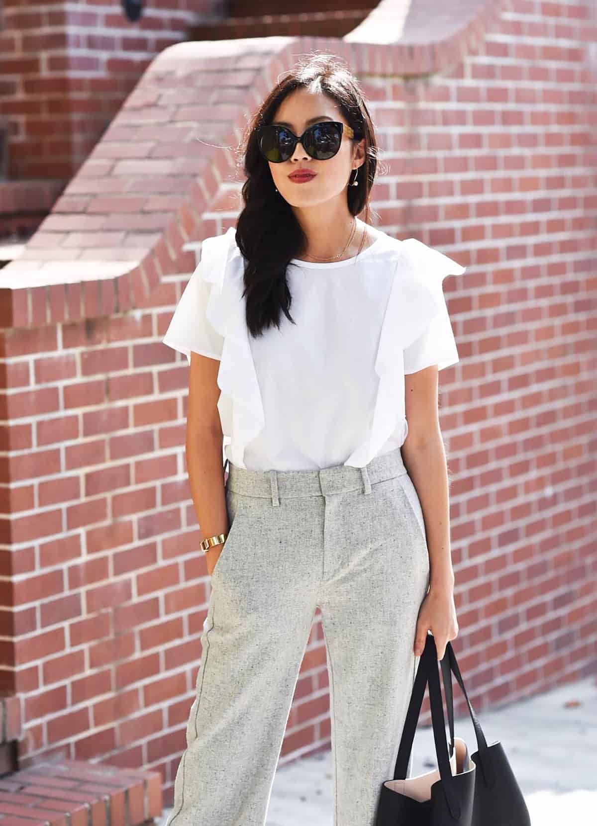 white ruffle-shoulder blouse paired with light grey tailored trousers office attire for summer