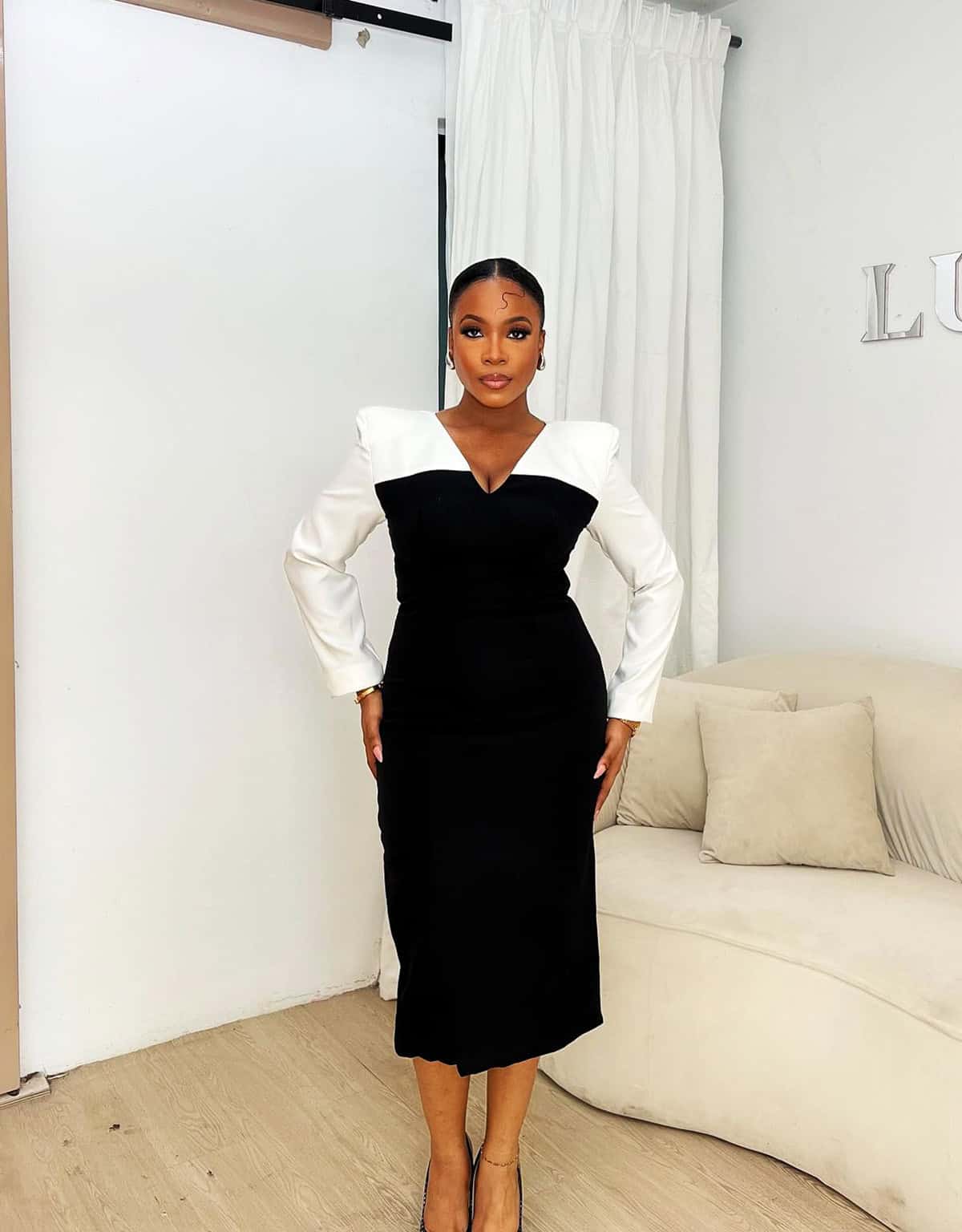black and white color-block structured midi dress with deep V-neckline and gold accessories for office attire for women over 40