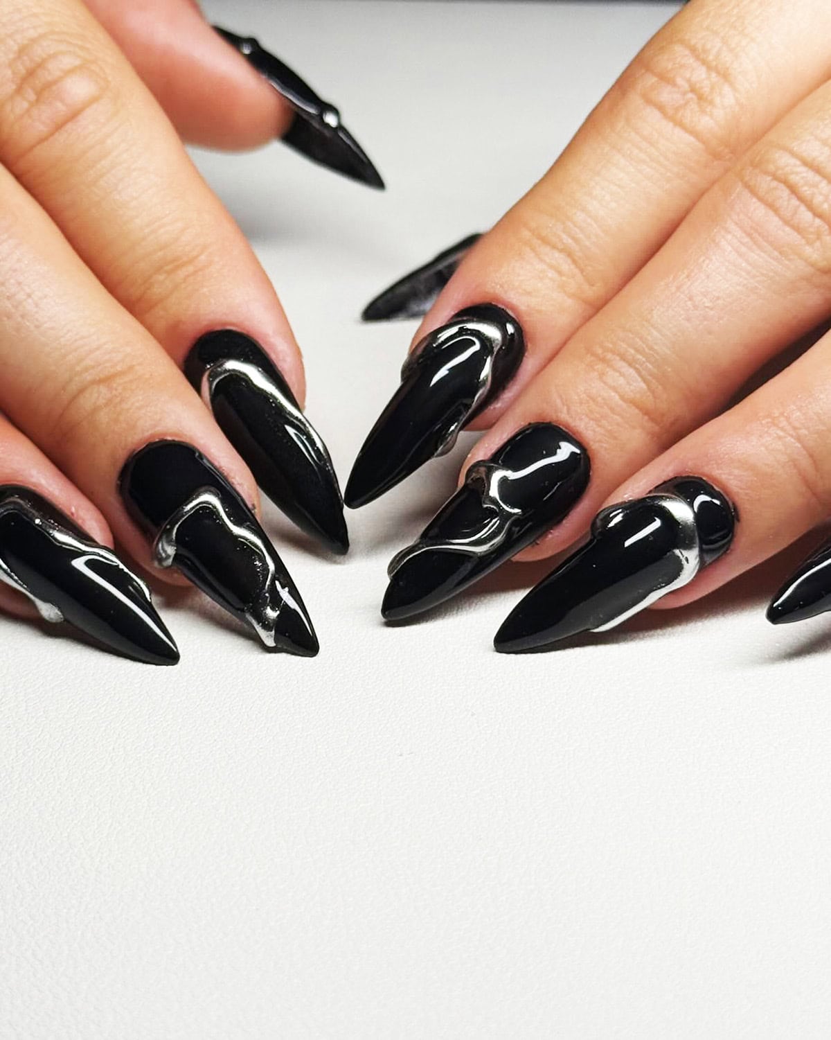 stiletto nails with liquid silver chrome swirl on black base black chrome nails