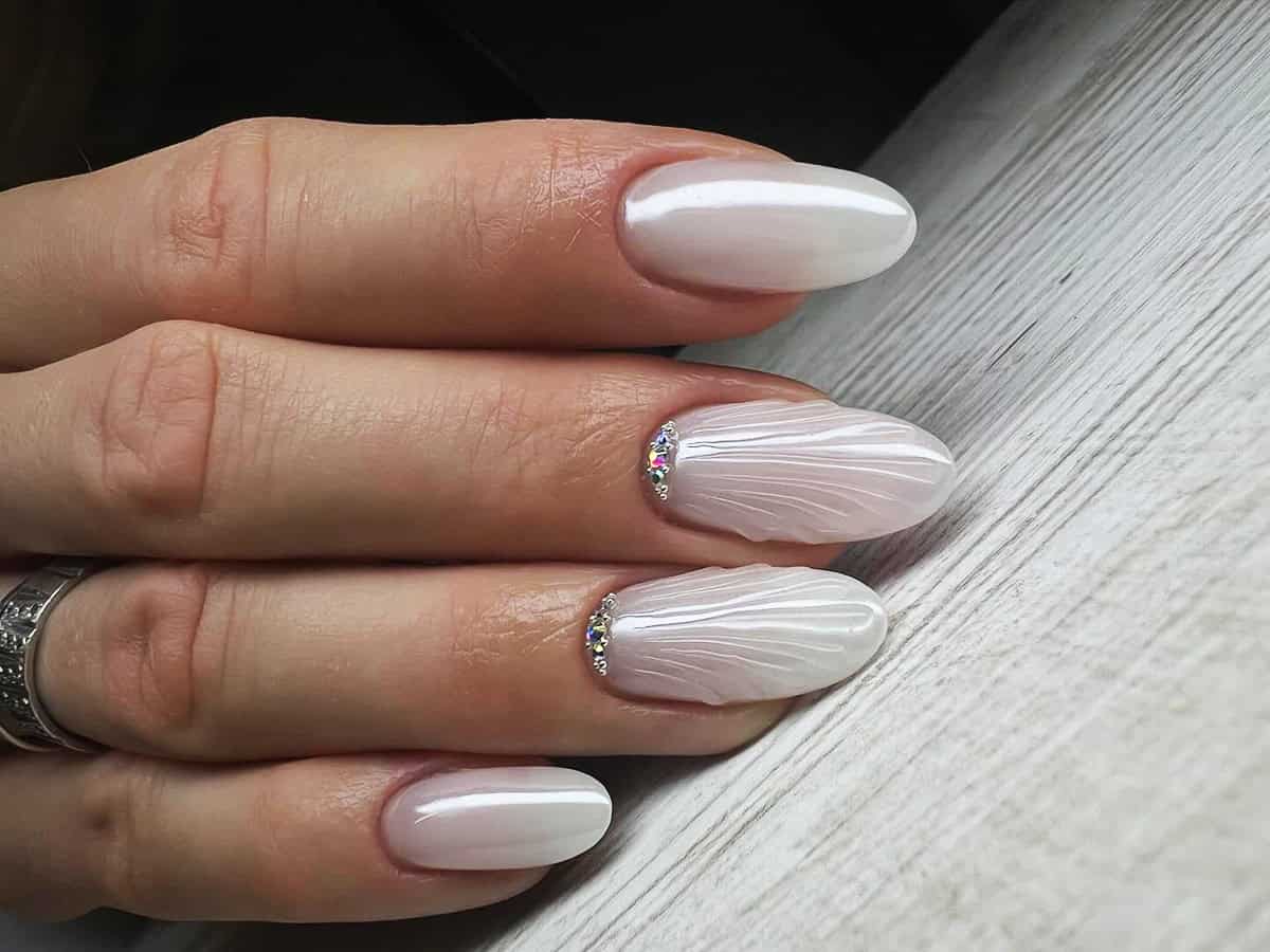 almond nails with textured pearl white chrome and rhinestone accents white chrome nails