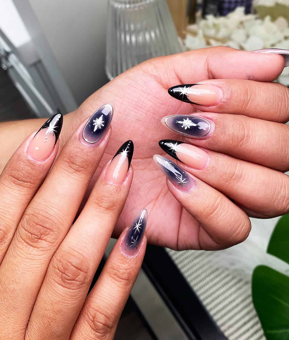 almond nails with black chrome tips and celestial star details black chrome nails