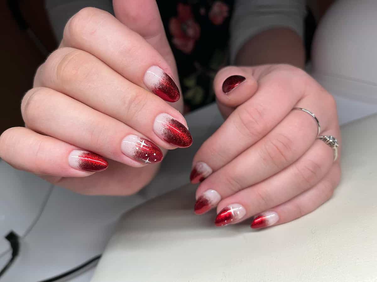 almond nails with soft nude to red chrome ombre fade glittery finish red chrome nails